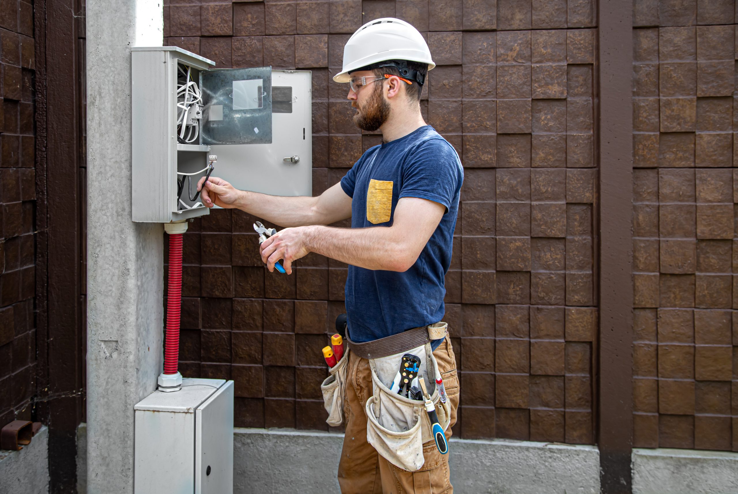 Electrician builder examines the cable connection in the electrical line in switchboard.